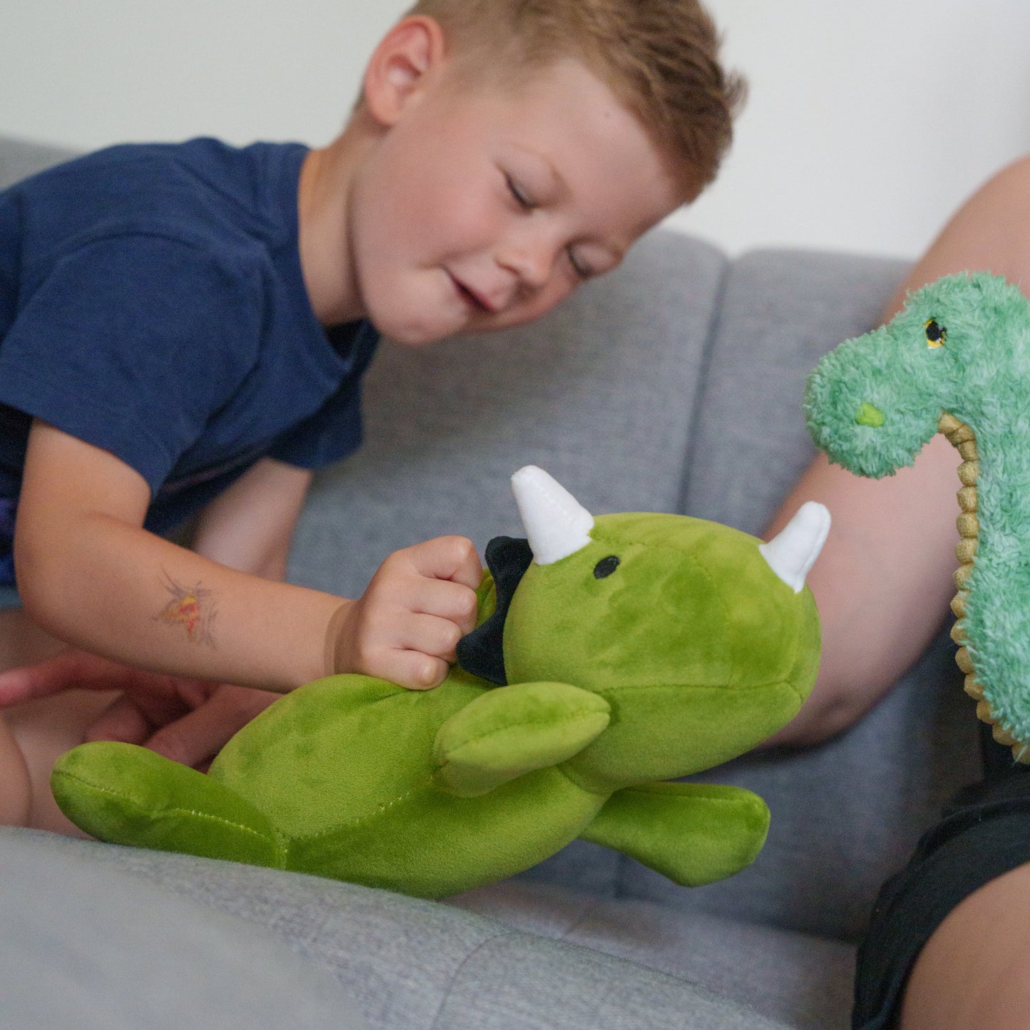 Child playing with a green plush toy on a couch