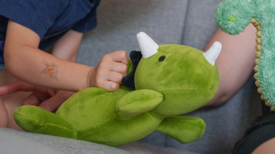 Child playing with a green plush toy on a couch